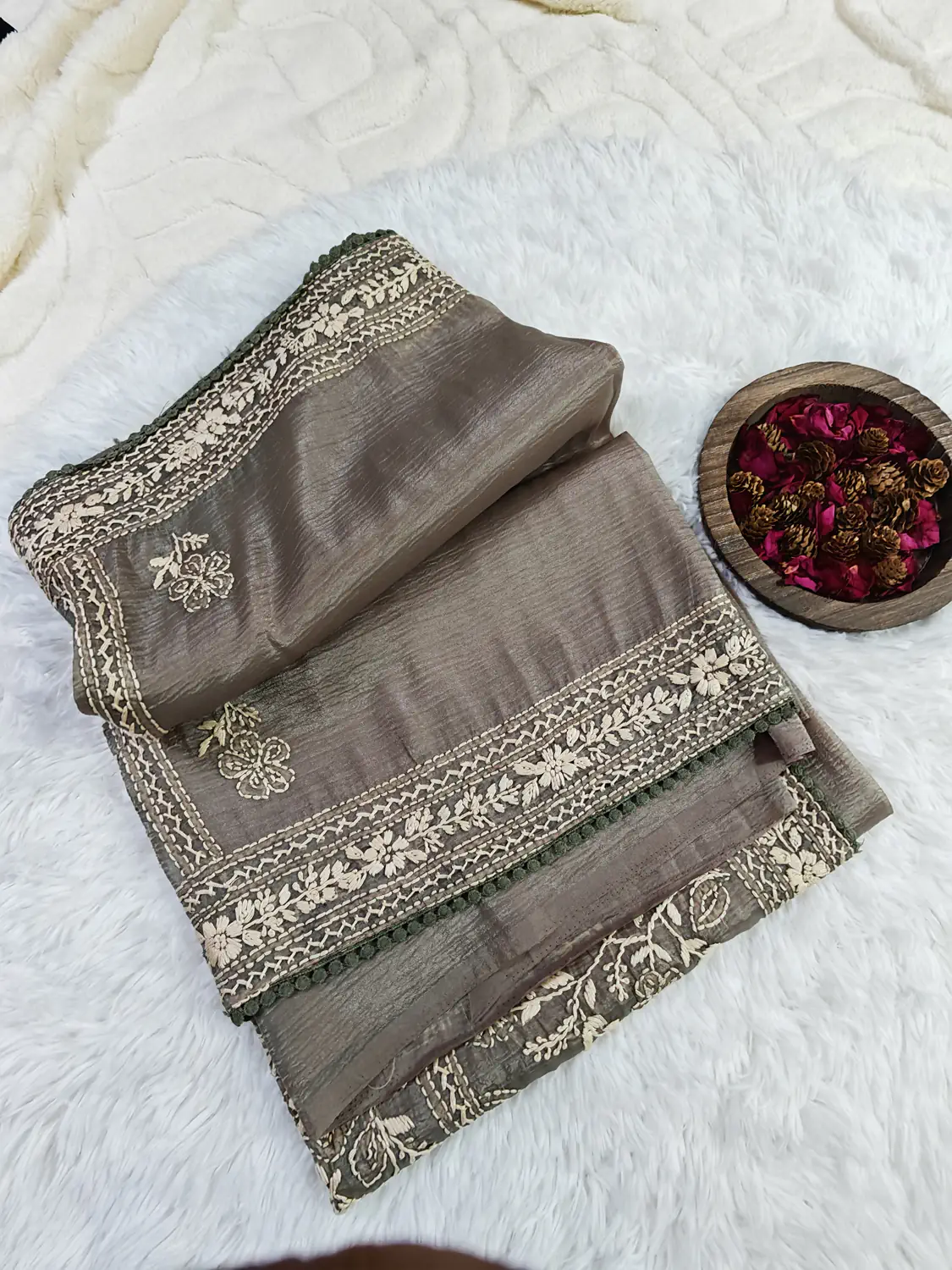 Greyish Green Crushed Organza Saree partly unfolded to show small motifs and floral border