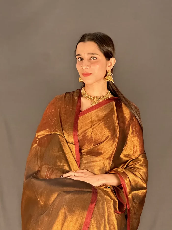 Close portrait showing the golden saree and red border