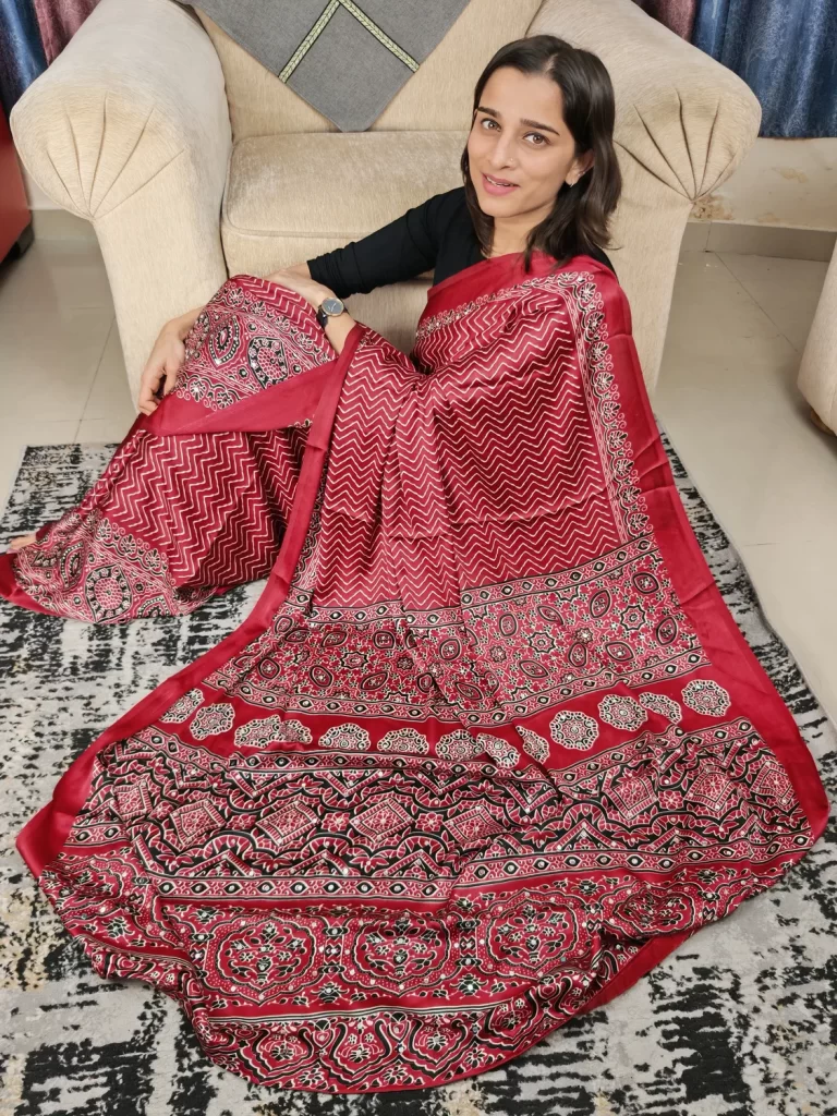 Maroon modal satin silk saree with chevron print and ornate pallu, seated view