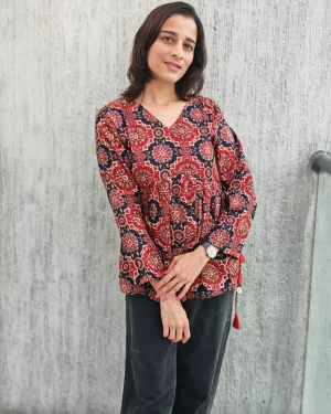 Rust Ajrakh peplum top with flared hem and side tassels, three-quarter view