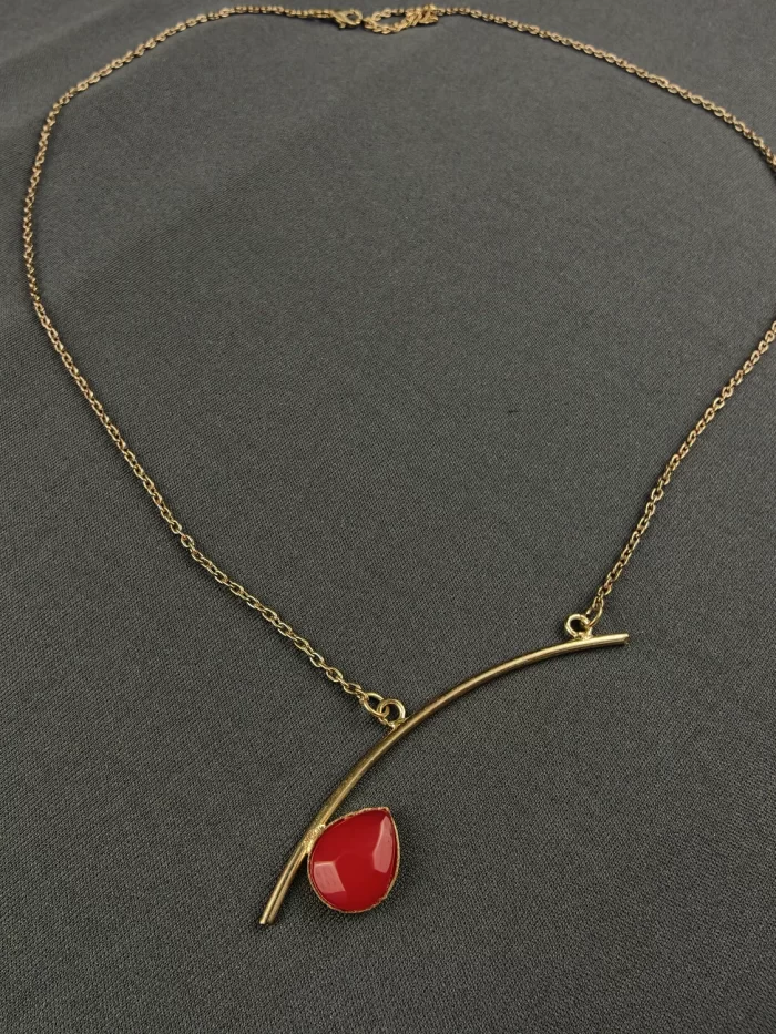 ASYMMETRIC BAR GEMSTONE NECK CHAIN Asymmetric Bar Gemstone Neck Chain with an angled gold-toned bar and red teardrop stone
