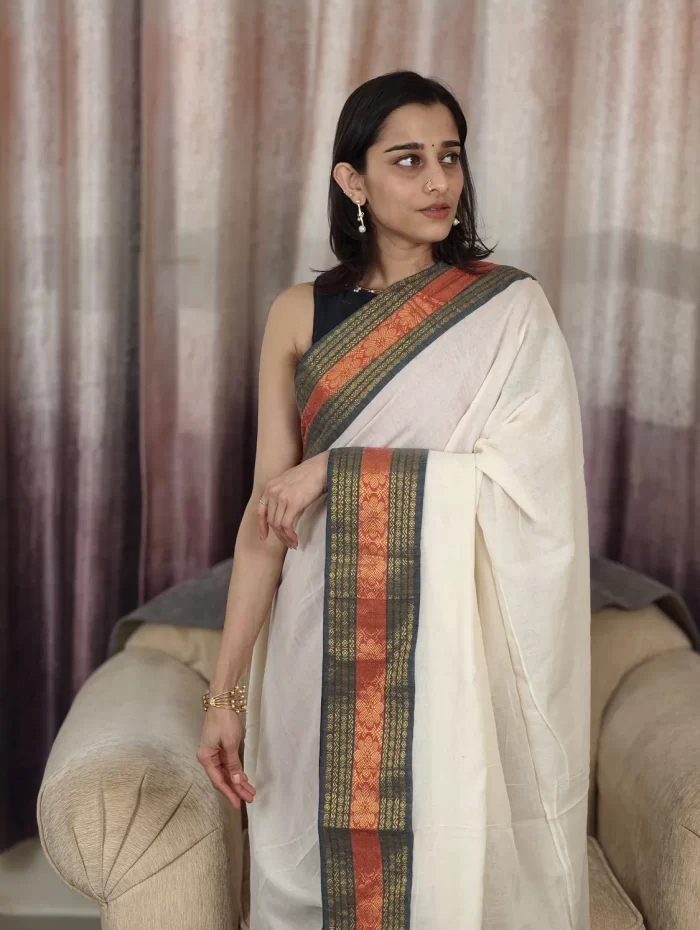 Offwhite Mulcotton Saree with Black & Orange Border (10) Three-quarter view of Off-White Mul Cotton Saree with black-orange border draped over the shoulder