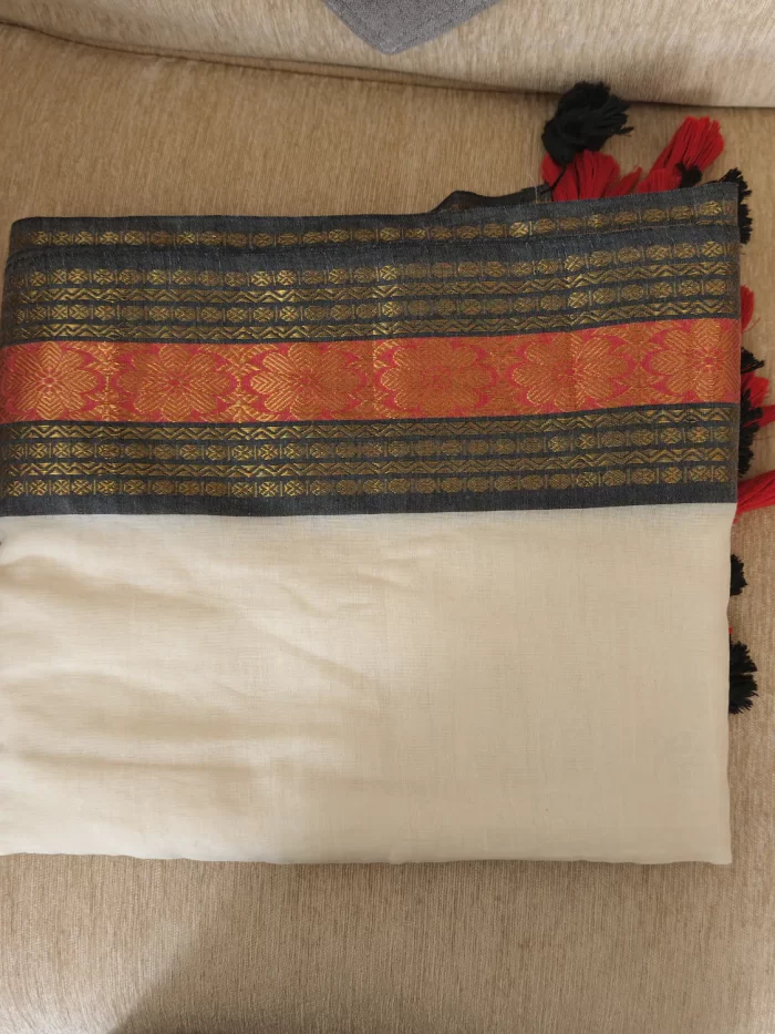 Offwhite Mulcotton Saree with Black & Orange Border (11) Folded Off-White Mul Cotton Saree showing the black-orange woven border and red-black tassels