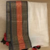 Offwhite Mulcotton Saree with Black & Orange Border (13) Folded full view of Off-White Mul Cotton Saree with black-orange woven border and tasselled edge