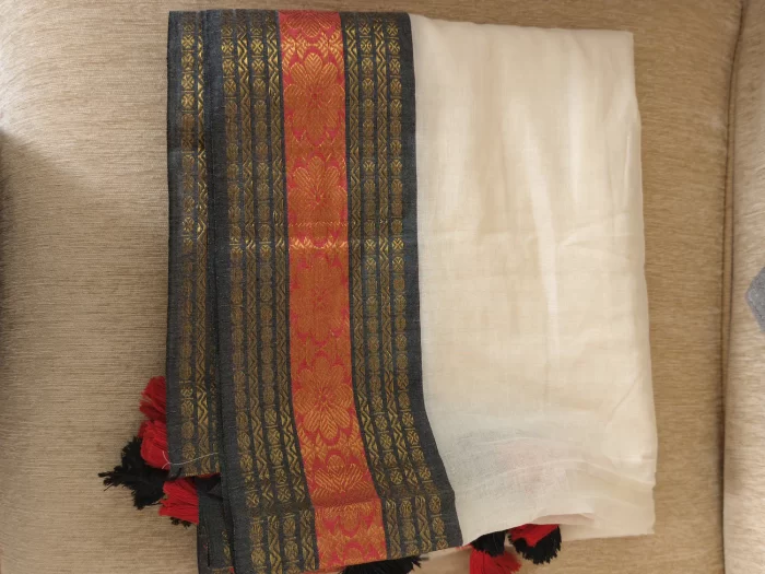 Offwhite Mulcotton Saree with Black & Orange Border (13) Folded full view of Off-White Mul Cotton Saree with black-orange woven border and tasselled edge