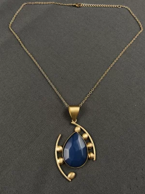 Sapphire Cosmic Tear Drop Neck Chain with a blue teardrop pendant and sweeping gold-toned lines