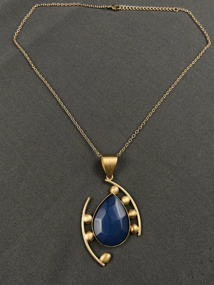 SAPPHIRE COSMIC TEAR DROP NECK CHAIN Sapphire Cosmic Tear Drop Neck Chain with a blue teardrop pendant and sweeping gold-toned lines