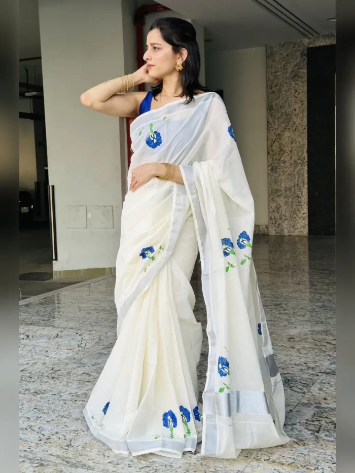 Shangupushpam Hand-Painted Saree – Side View Full-length side view of Shangupushpam ivory saree with blue flowers and silver border